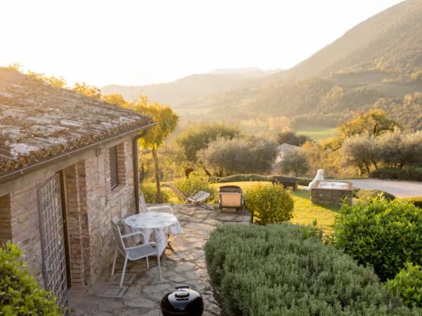 Casa rústica de piedra con vistas a colina al atardecer.