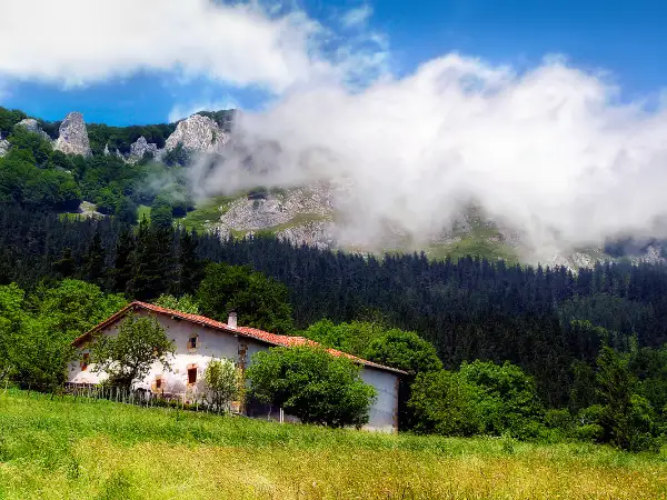 Casa rural bajo un cielo con nubes.