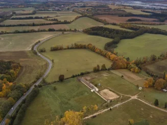 Vista aérea de terrenos rústicos y parcelas agrícolas, con caminos y zonas de bosque mixto.