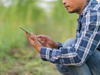 Agricultor utilizando uma tablet no campo, ilustrando a digitalização do setor agrícola.